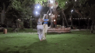 two women are standing next to each other in a park at night .