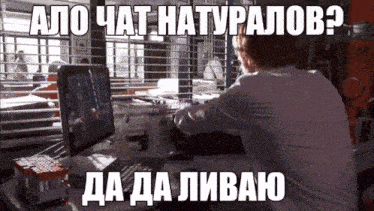 a man sits at a desk with a computer and a foreign language caption