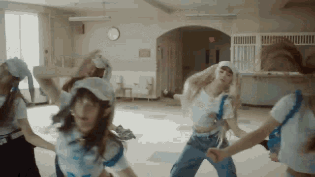 a group of girls are dancing in a room with an exit sign