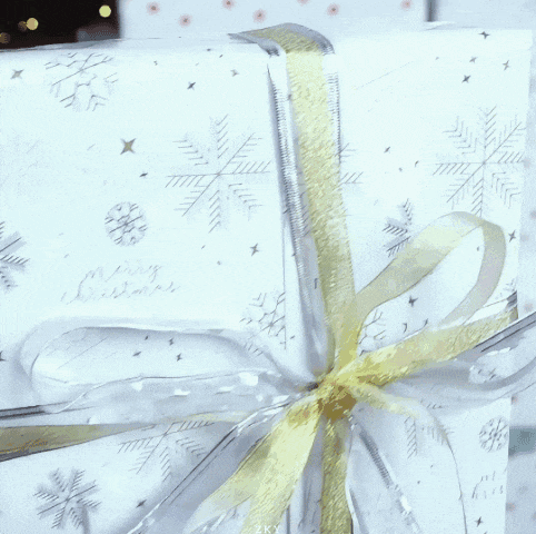 a gift wrapped in white paper that says merry christmas on it
