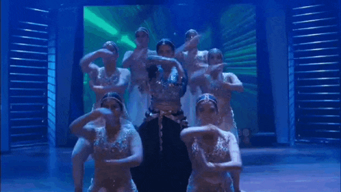 a group of dancers are dancing on a stage in front of a large screen .
