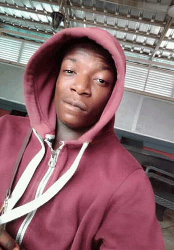 a young man wearing a maroon hoodie with a white zipper