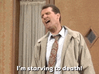 a man in a suit and tie is standing in front of a door and saying i 'm starving to death .