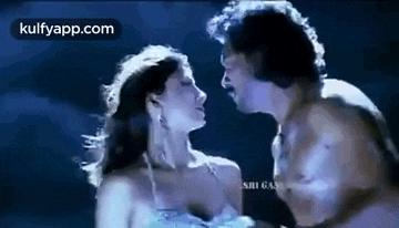 a man and woman are kissing in a dark room .