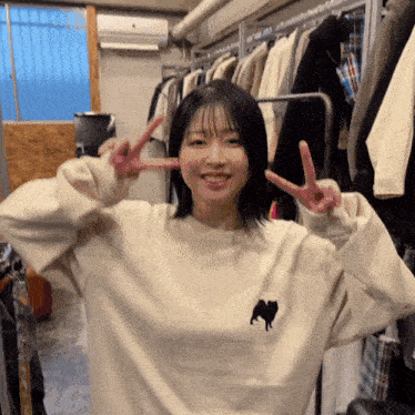 a woman wearing a white sweater with a dog on it giving a peace sign