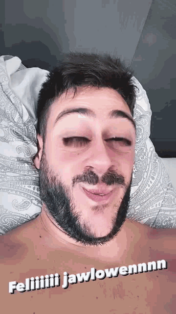 a man with a beard is laying in bed with his eyes closed and a caption that says feliiiiii jawlowennnn