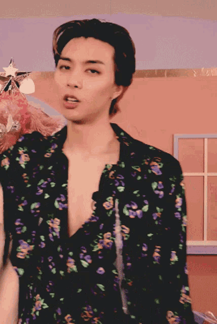 a man wearing a black shirt with purple flowers and green leaves