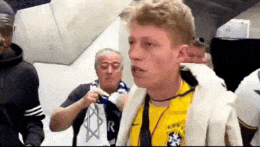 a man in a yellow shirt with the letter r on it is talking to another man