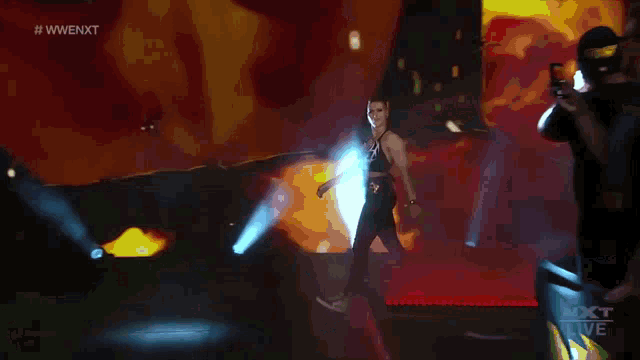 a female wrestler is walking on a stage in front of a screen that says nxt live