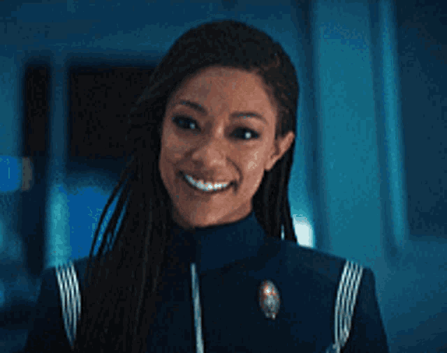 a woman with dreadlocks is smiling in a blue uniform
