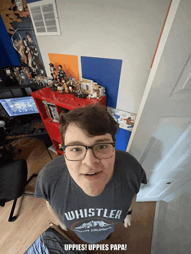 a man wearing a whistler t-shirt is standing in a room
