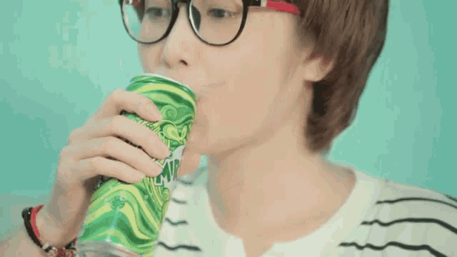 a person wearing glasses is drinking from a green can with the word lime on it