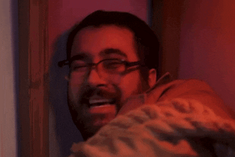 a man with glasses and a beard is smiling in a red room .