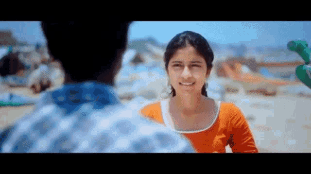 a man and a woman are looking at each other on a beach and smiling .