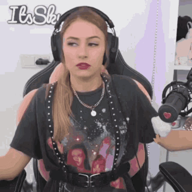 a woman wearing headphones is sitting in front of a sign that says it 's shy