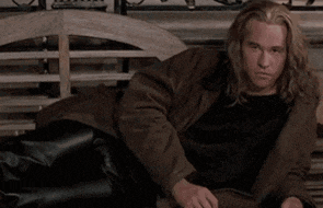 a man with long hair is laying down on a bench
