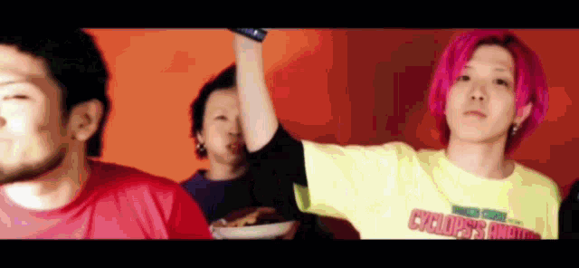 a man with pink hair is wearing a yellow t-shirt that says cyclists on it