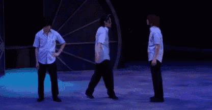 three men are standing on a stage dancing together .