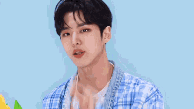 a young man in a plaid shirt is making a funny face while holding flowers .