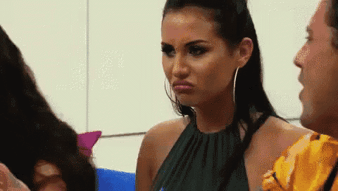 a woman in a black dress is making a funny face while a man looks on .
