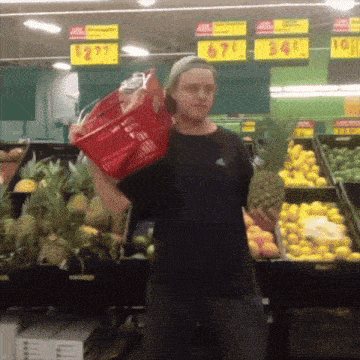 a man carrying a red basket in a grocery store with a price tag that says $ 2.79