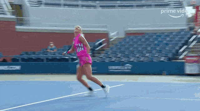 a woman in a pink top and shorts is running on a tennis court while holding a tennis racquet