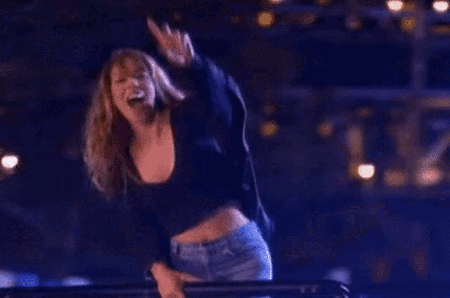 a woman in a black crop top and jeans is giving a middle finger