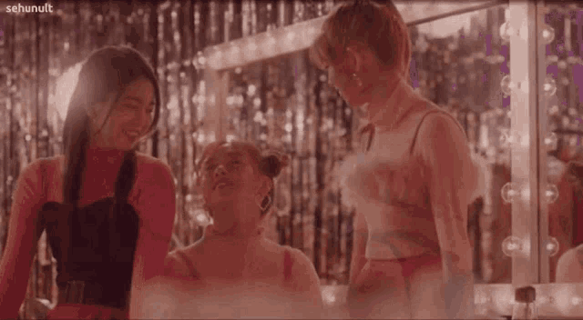 three girls are standing next to each other in front of a mirror with sehunult written on the bottom right corner