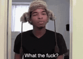 a man wearing a furry hat is standing in a doorway and asking what the fuck .