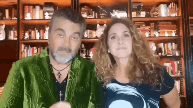 a man and a woman are standing next to each other in front of a bookcase .
