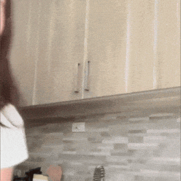 a woman in a white shirt is standing in a kitchen