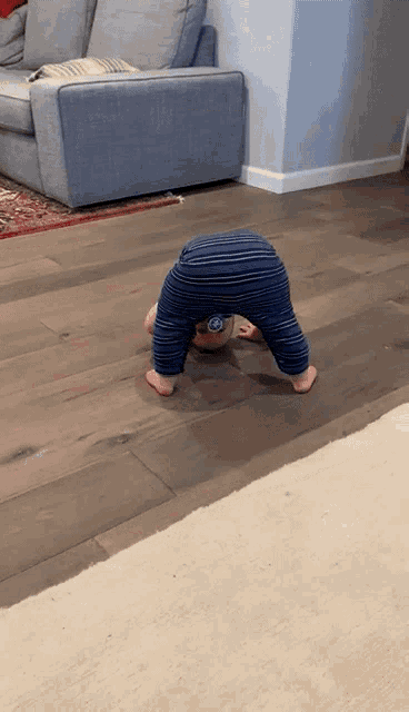 a baby is doing a handstand on the floor in a living room