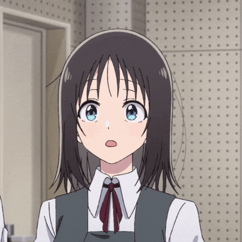 a girl with short black hair and blue eyes is wearing a white shirt and a gray vest