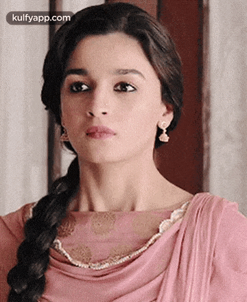 a close up of a woman 's face with a braid and earrings .