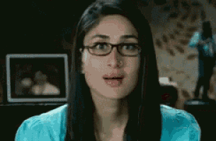 a woman wearing glasses and a blue shirt is making a funny face