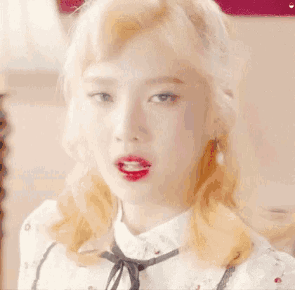 a close up of a woman 's face with blonde hair and red lips .