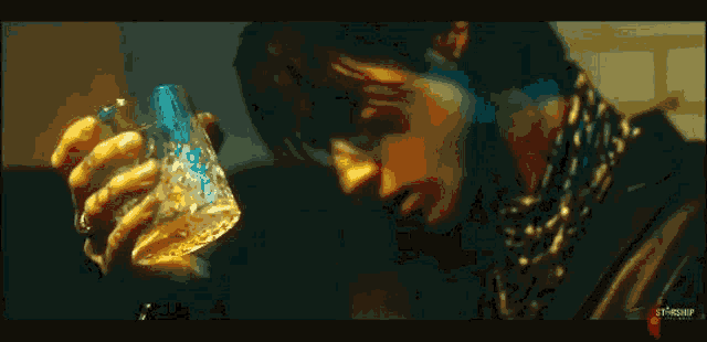 a man is holding a glass of whiskey in his hands .