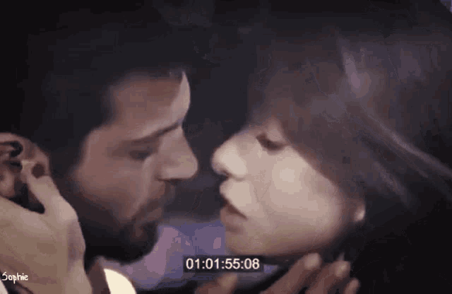 a man and a woman are kissing in front of a timer that reads 01 : 01 : 55 : 06 .