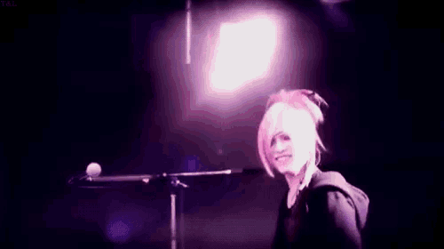 a person is standing in front of a microphone on a stage and waving .