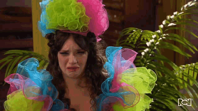 a woman wearing a clown costume is crying and has the letter c on her face