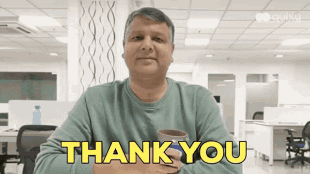a man in a green shirt is holding a cup and saying thank you .