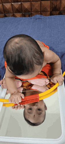 a baby is looking at its reflection in the mirror