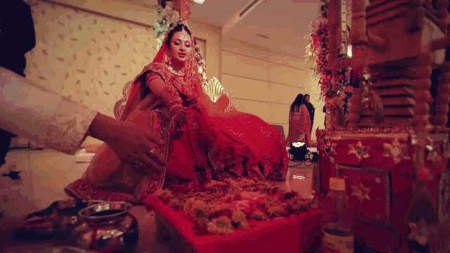a bride in a red dress is being helped by a man in a white dress