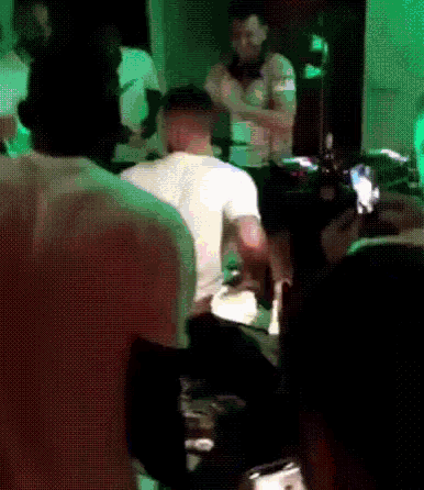 a group of people are gathered in a dark room with a green light behind them