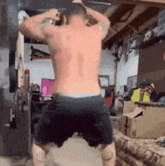 a man without a shirt is doing squats in a room .