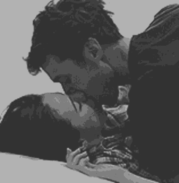 a man and woman are kissing on a bed .