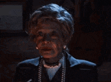 a woman is smoking a cigarette in a dark room and smoke is coming out of her mouth .
