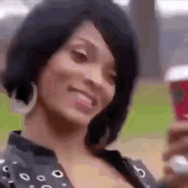 a woman is smiling while holding a cup of coffee in her hand .