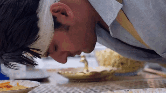 a man with a bandage on his head smells a bowl of food