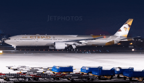 an etihad airplane sits on a runway at night